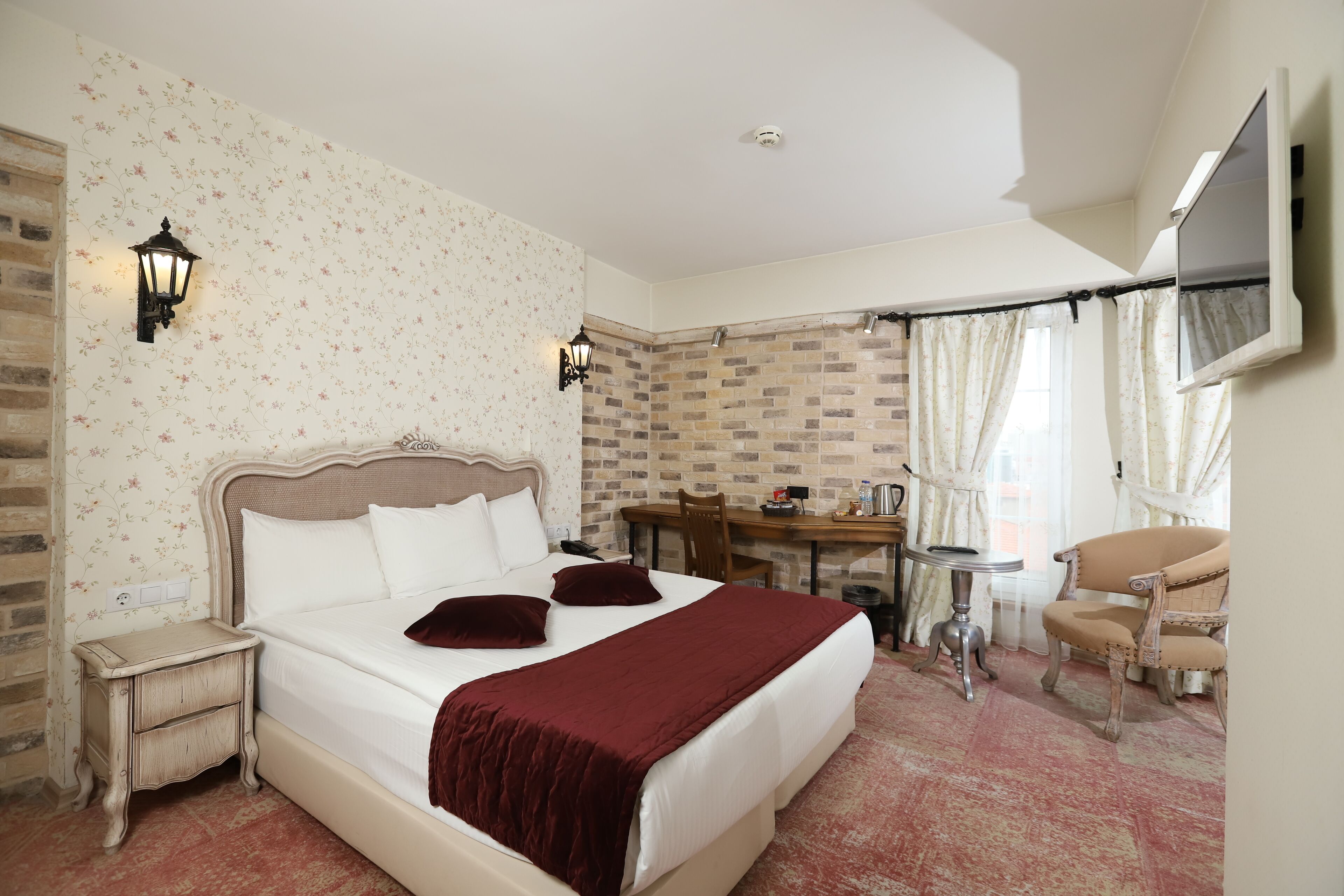 Habitación de hotel con una cama grande, un escritorio, una silla y un televisor montado en la pared.