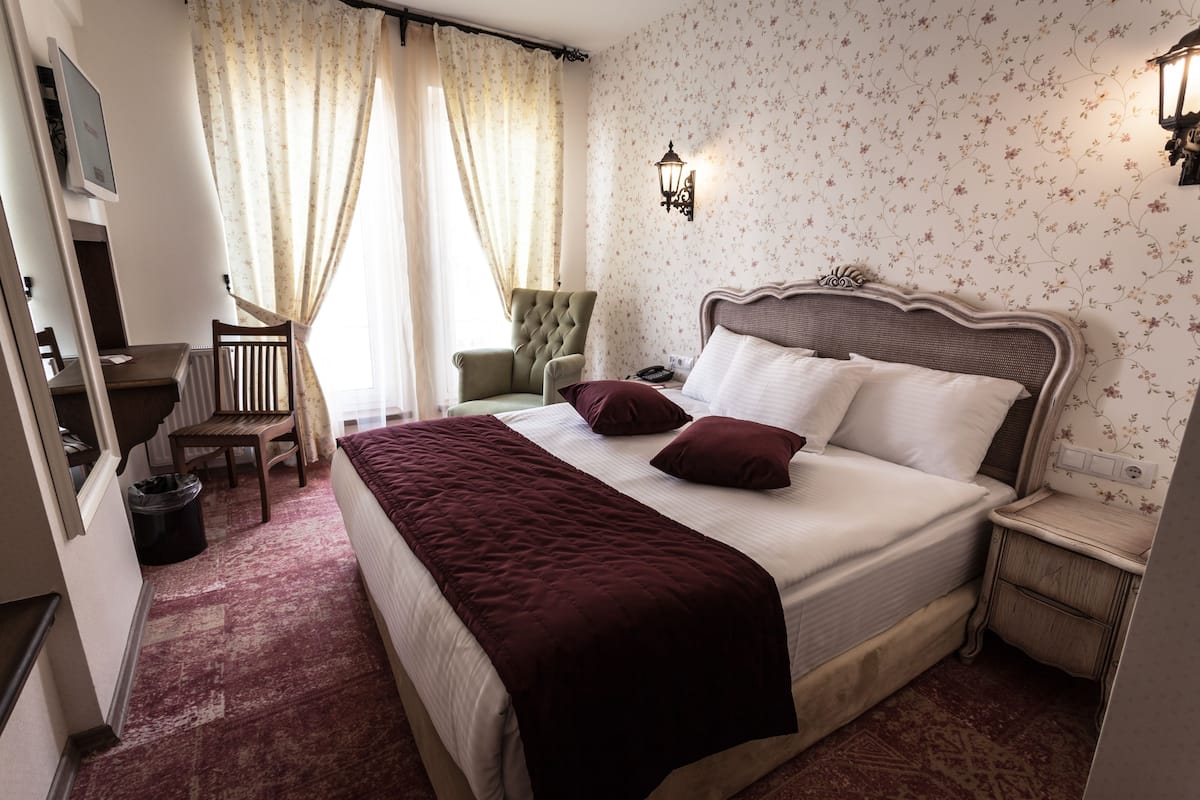 A bedroom with a large bed, a desk, a chair, and a nightstand.