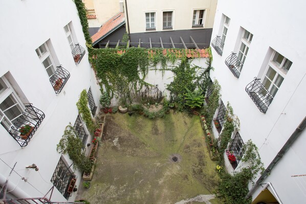 A courtyard with white walls, multiple windows, and balconies with potted plants. - Prague Siesta Apartments (Prague)