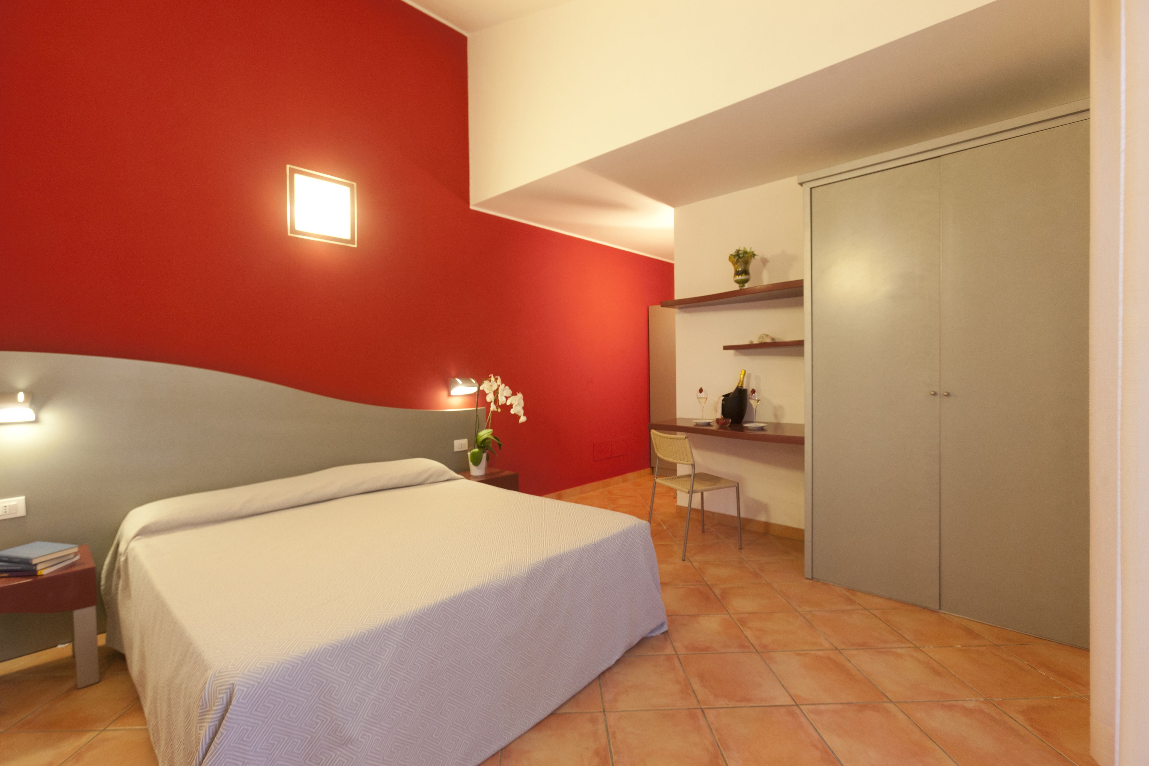 A bedroom with a bed, bedside table, chair, desk, and wardrobe.