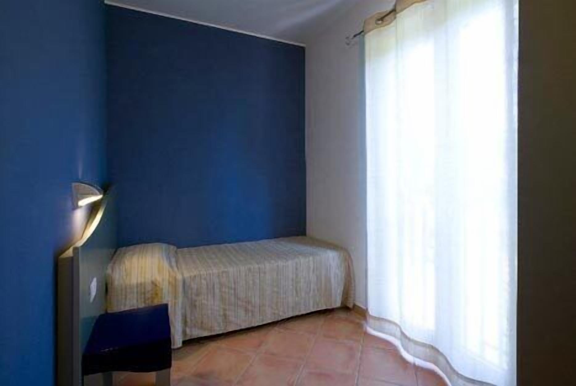 Une petite pièce avec un lit, une chaise et une lampe.