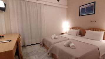 A hotel room with two beds, a desk, a lamp, and a picture on the wall.