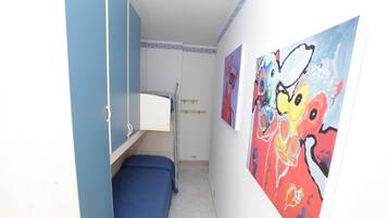 Habitación pequeña con literas, una mesita y una pared decorada con cuadros abstractos coloridos.