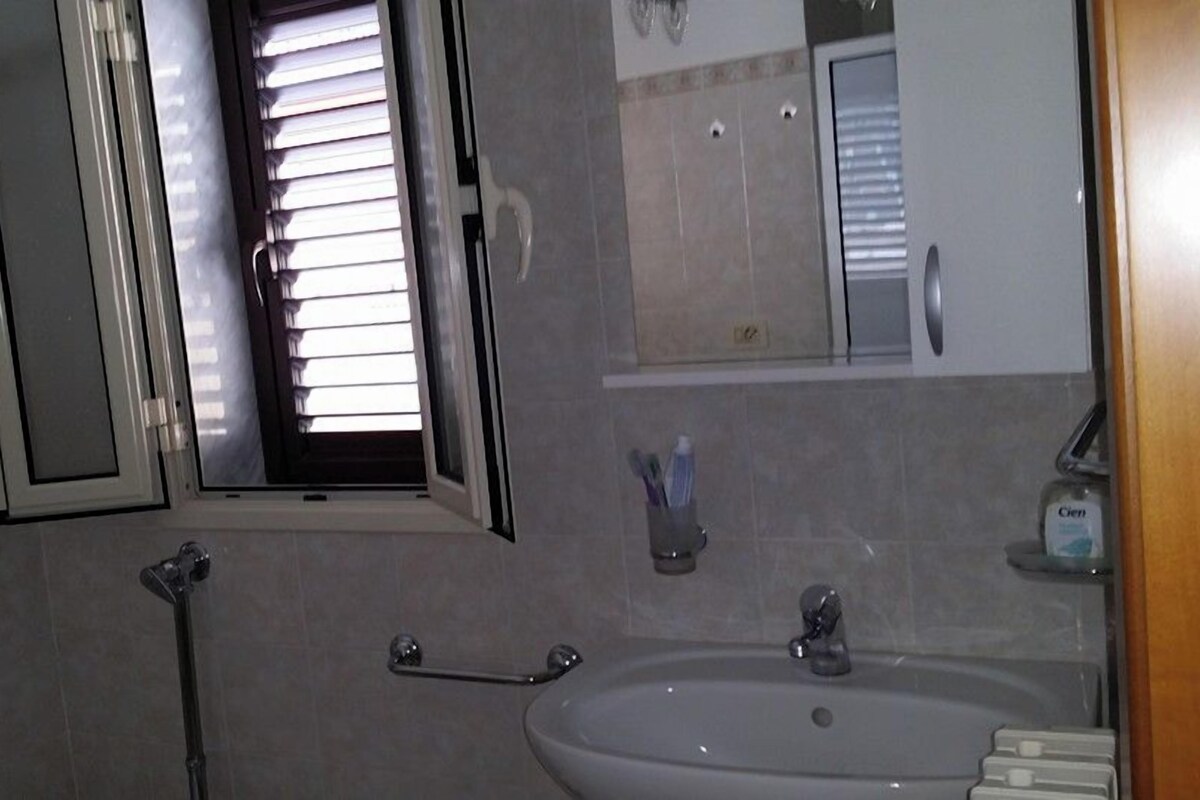 A bathroom with a sink, mirror, and window.