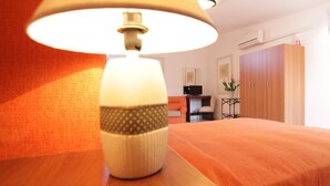 Ett rum med en säng, en lampa, ett skrivbord med en dator och en garderob.