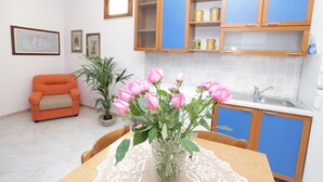 Ett kök med blå skåp, en diskho och ett matbord med en vas med rosa blommor.