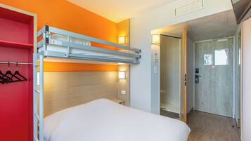 Ein Hotelzimmer mit Etagenbett, einem roten Kleiderschrank und einer Duschkabine.