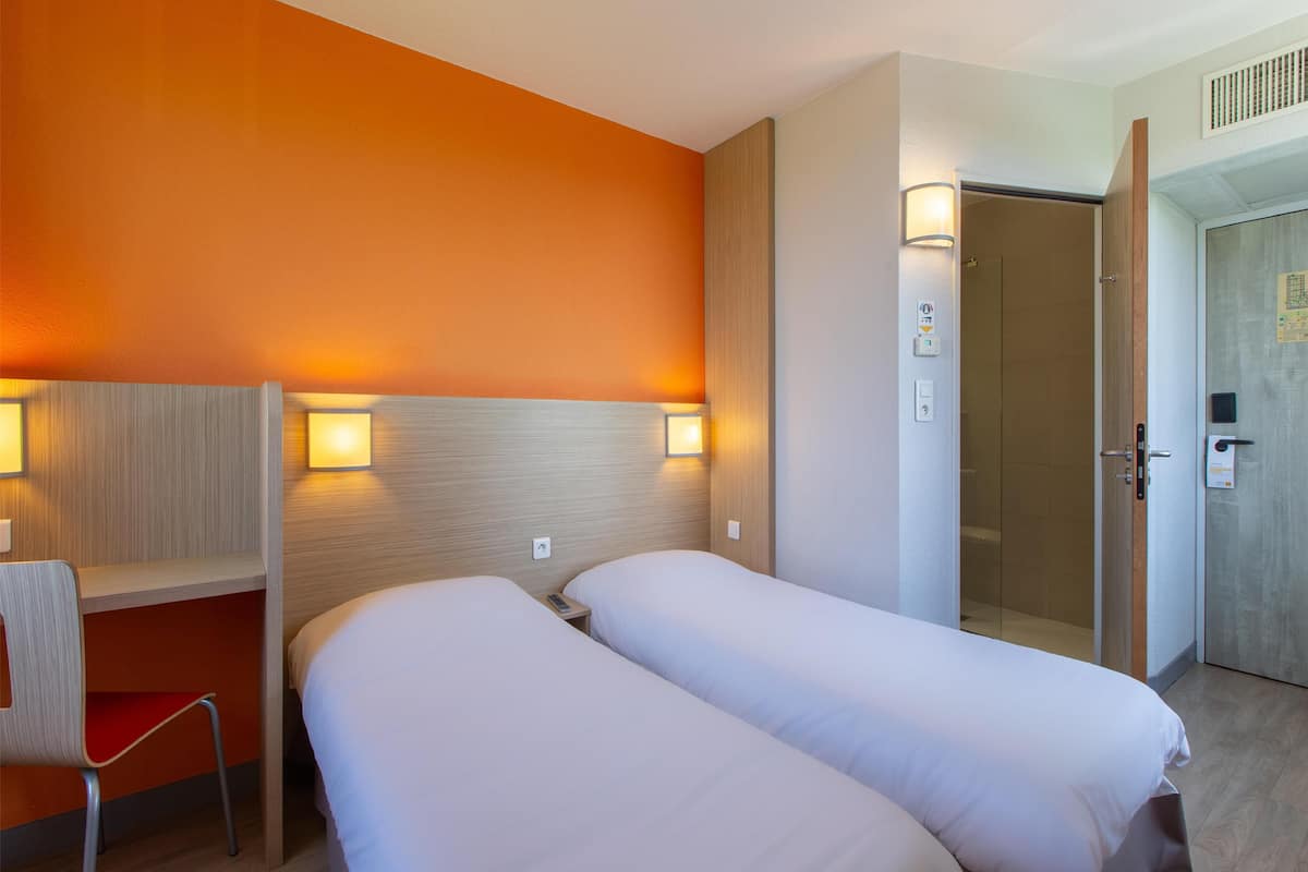 Une chambre d’hôtel avec deux lits, un bureau et une chaise.