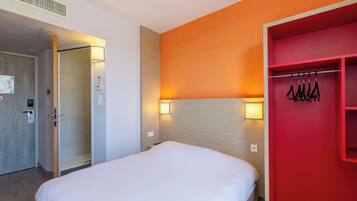 Ein Hotelzimmer mit Bett, Schrank und einer Tür mit Lichtschalter.