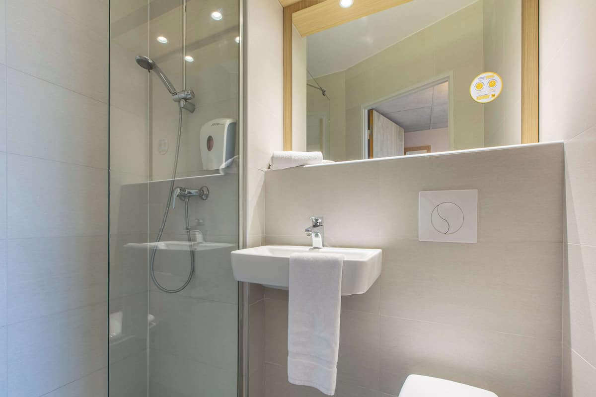 Une salle de bain moderne avec une douche à parois de verre, un lavabo blanc et des toilettes.