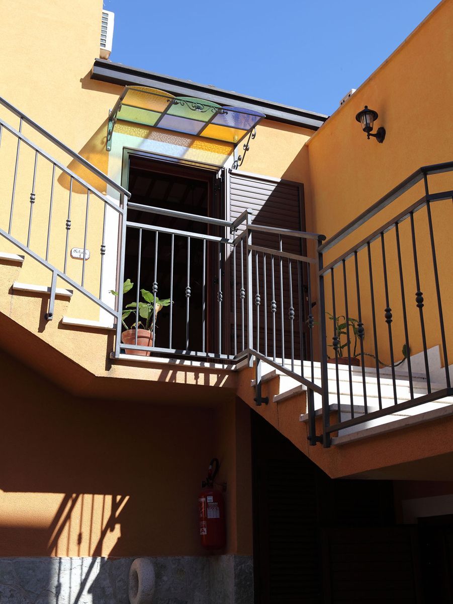 Un edificio de varios niveles con balcón, extintor y planta en maceta.