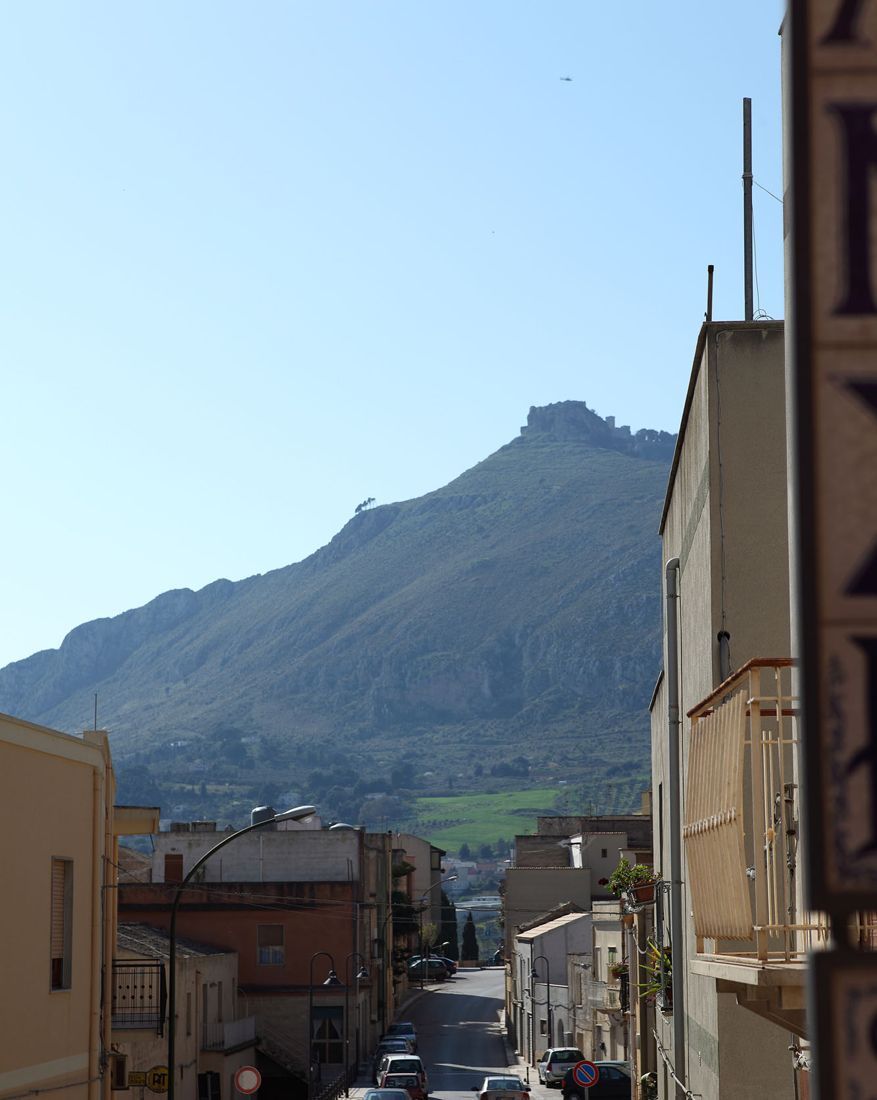 A narrow street with buildings on either side and a mountain in the background.