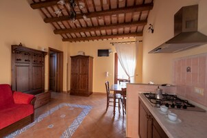 Una cocina compacta con estufa a gas, armarios de madera y un comedor con sillas y mesa.