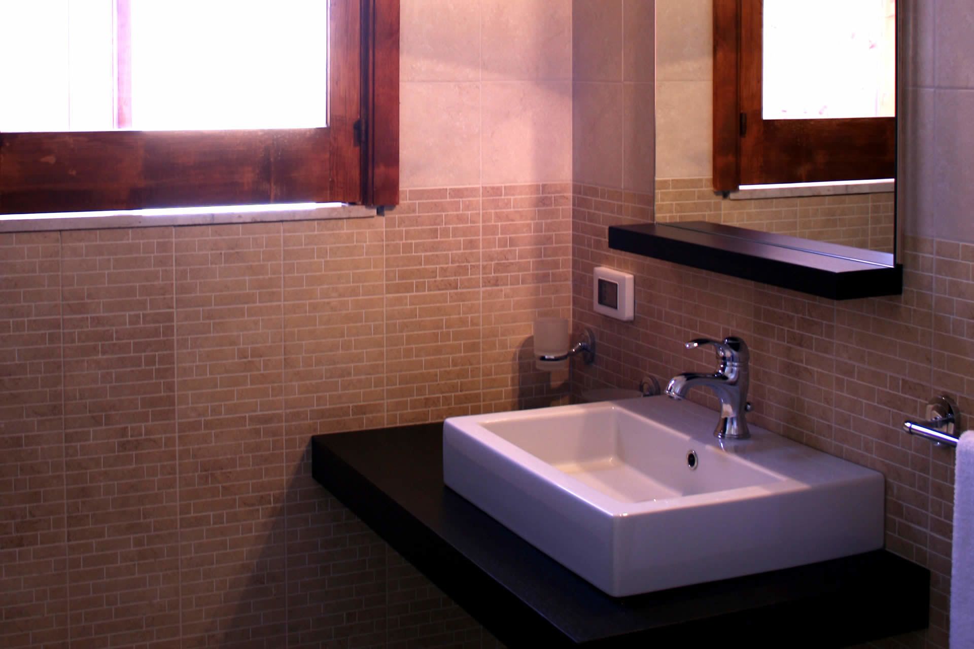 A bathroom with a white sink, a mirror, and a window.
