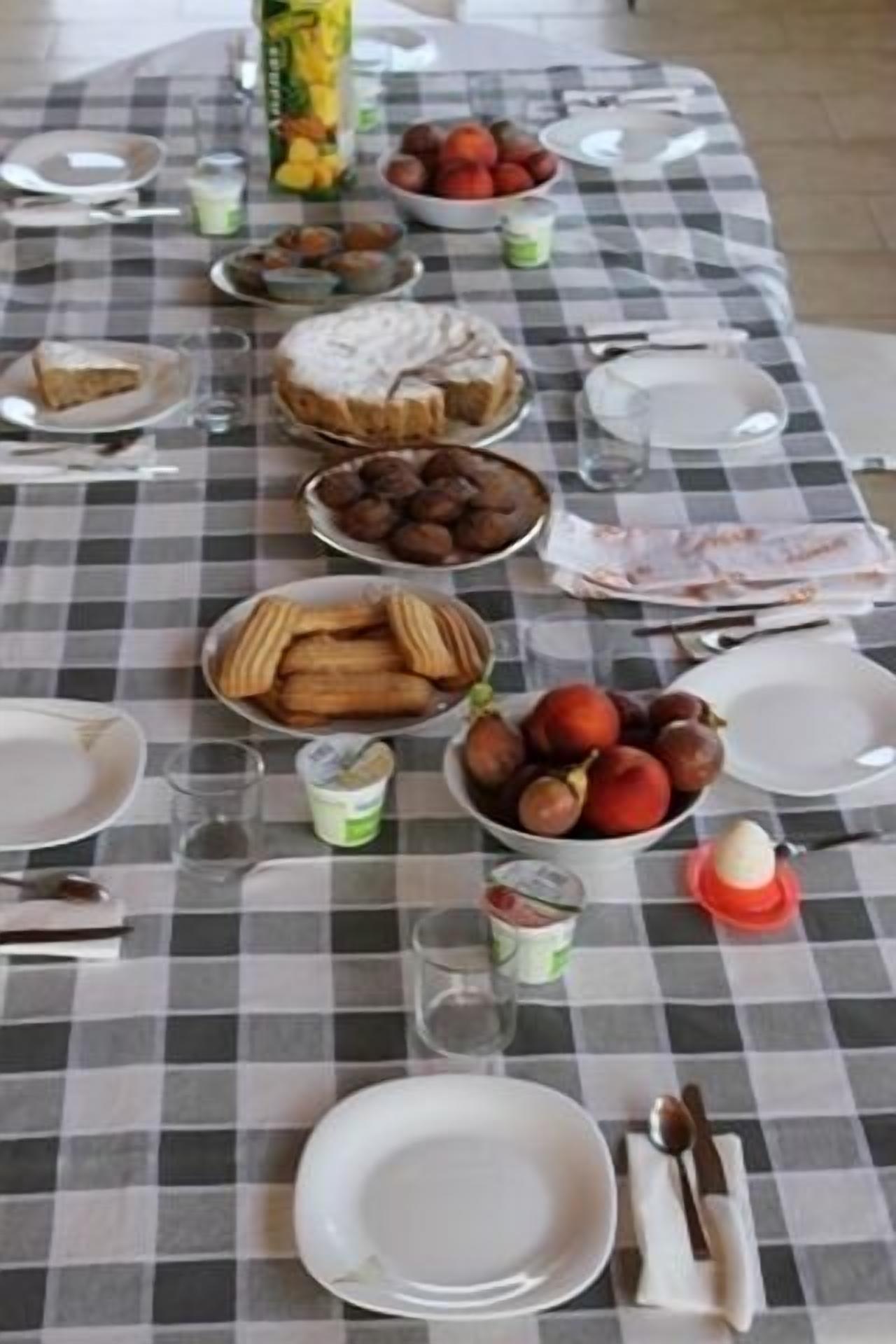 Una mesa dispuesta con diversos platos, incluyendo una tarta, frutas y pasteles, que sugiere un ambiente para comer.