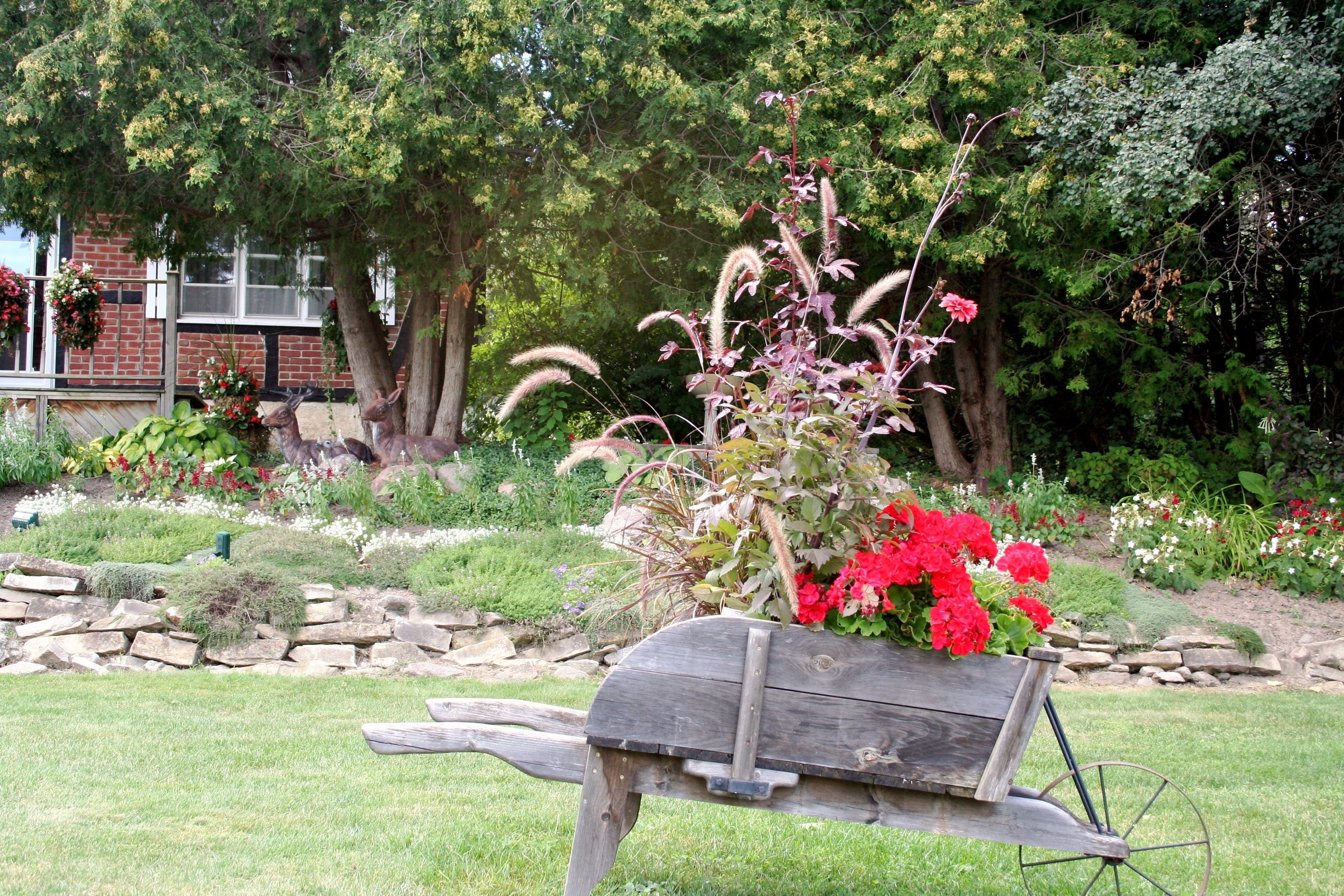 A rustic wooden bench with a flower arrangement in a garden setting.
