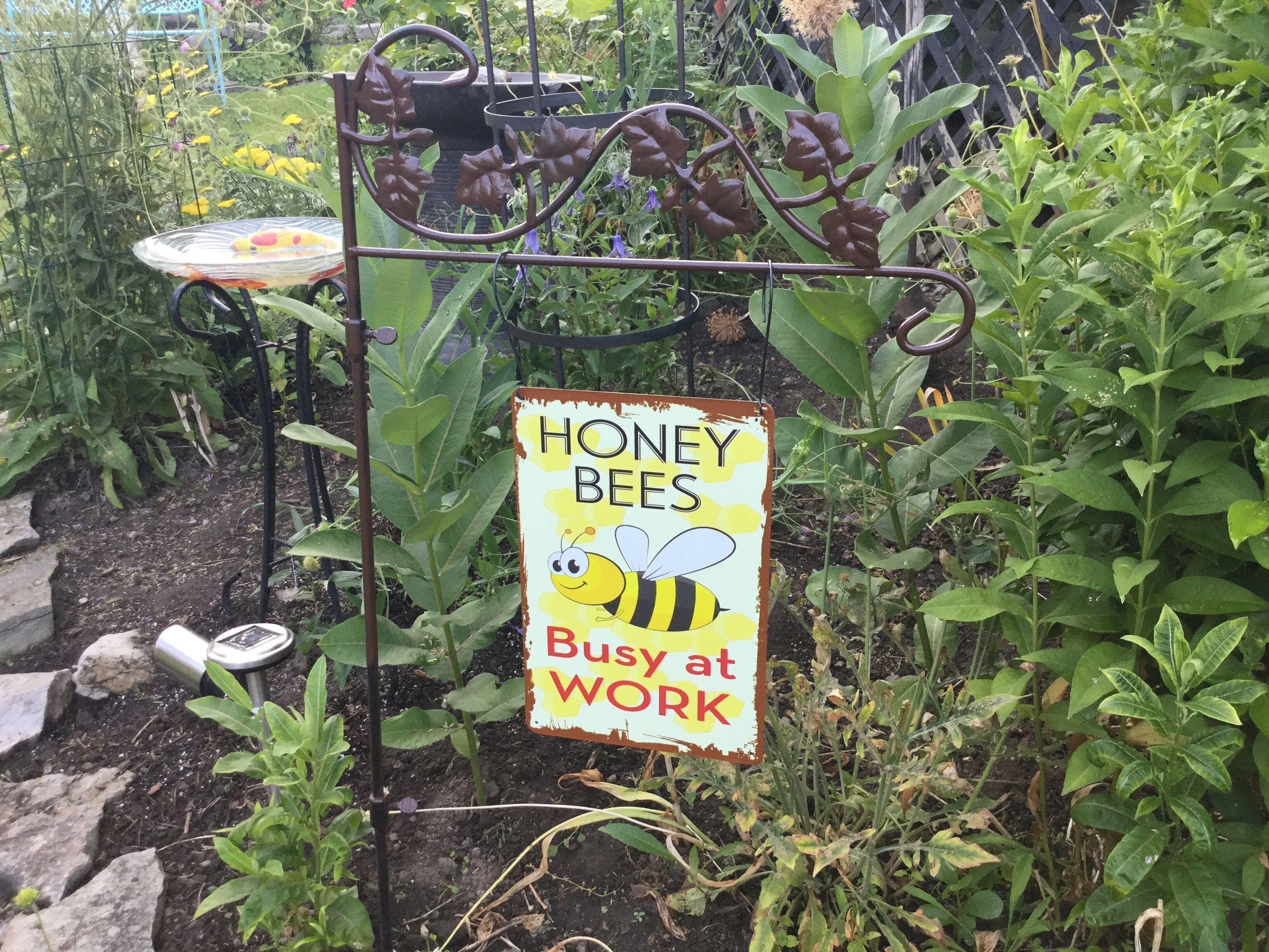 Un jardín con un cartel que dice "HONEY BEES Busy at Work".