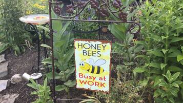 Un jardín con un cartel que dice "HONEY BEES Busy at Work".