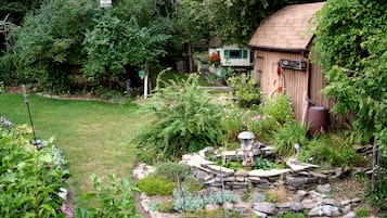 Ein Garten mit einer Holzlagerhütte, einem Vogelhaus und einem Steinfountain.