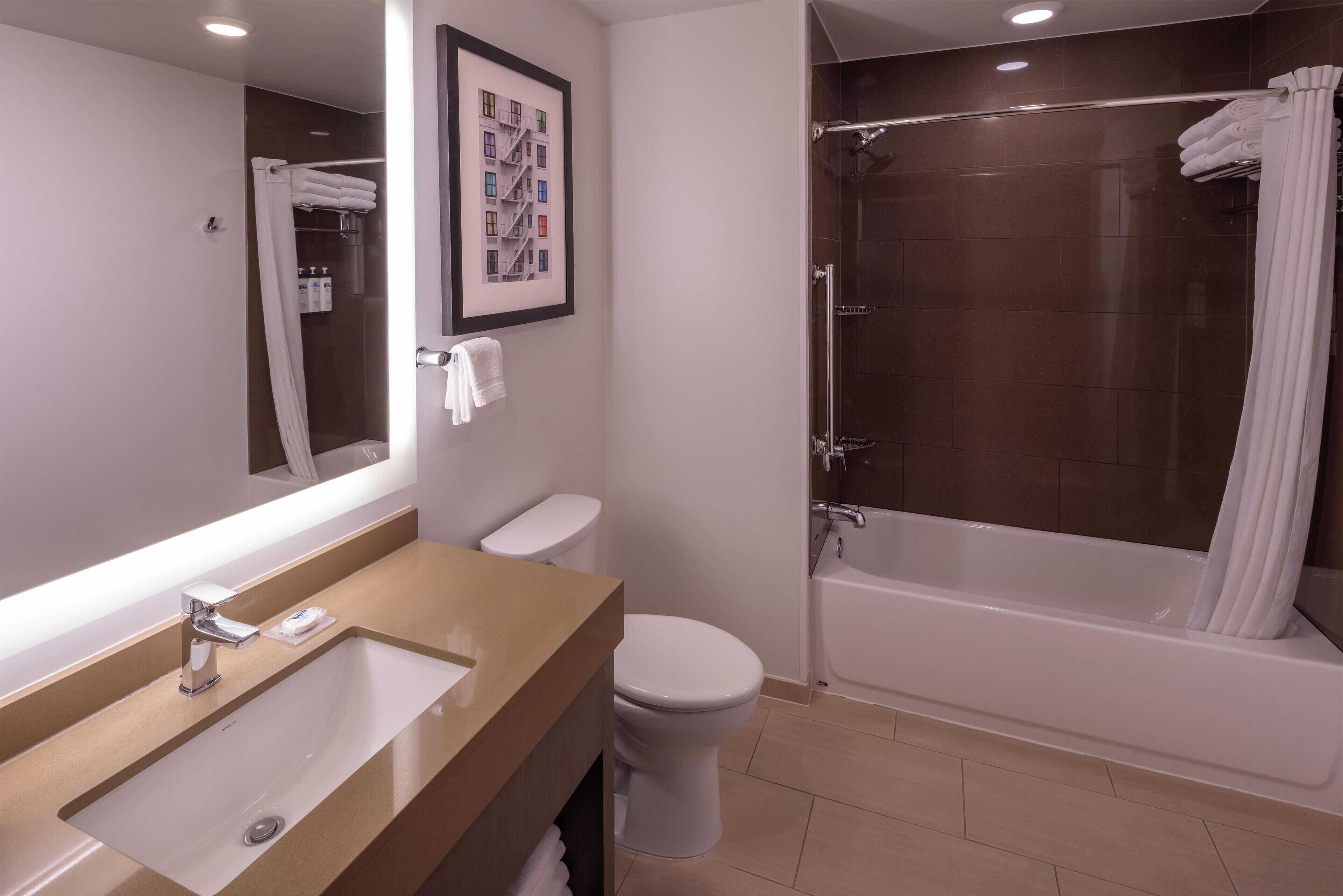 A modern bathroom with a sink, toilet, and bathtub.
