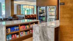 A hotel lobby with a marble reception desk, seating area, and a refrigerated display case. - Hyatt House Seattle/Downtown (Seattle)
