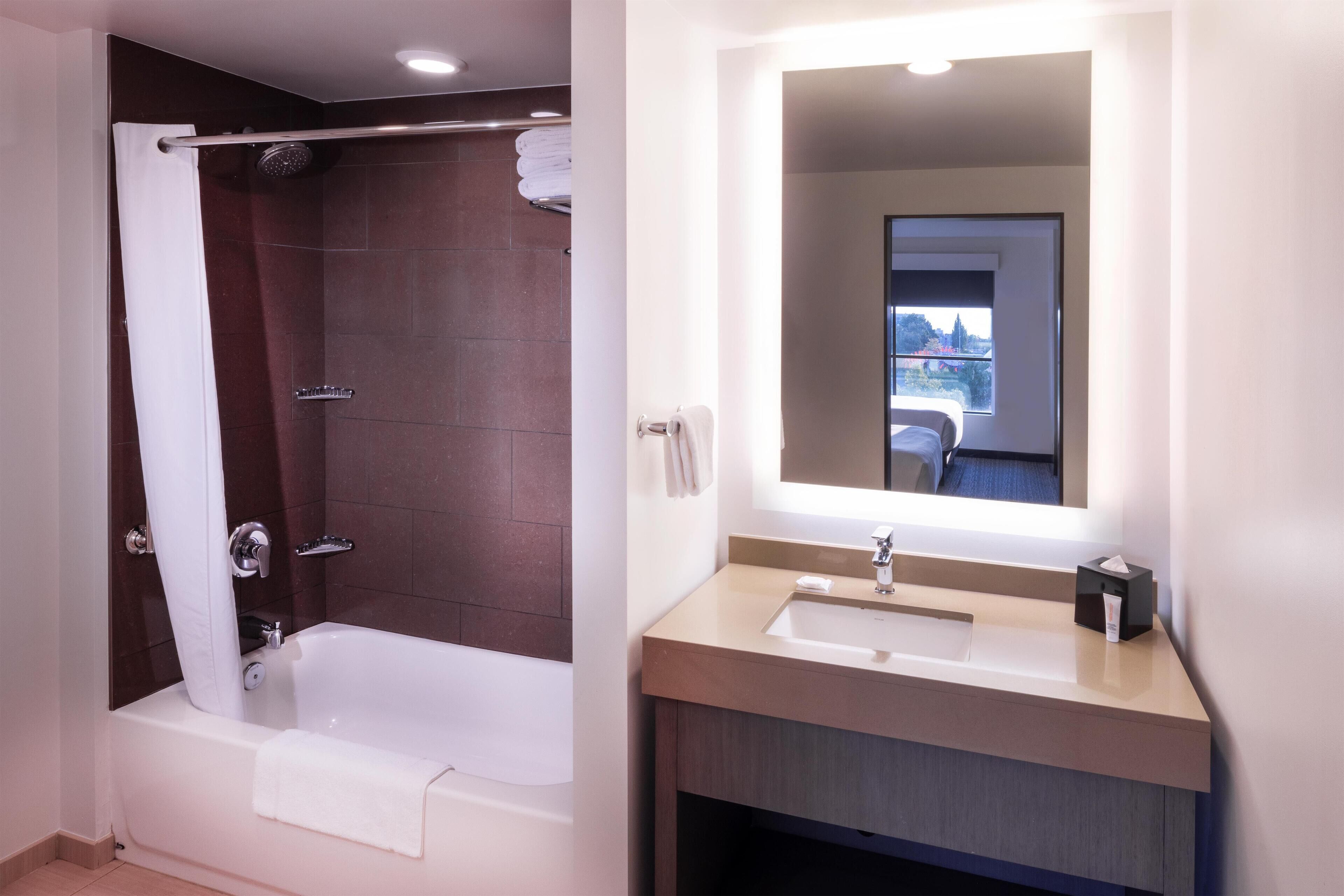 A modern bathroom with a bathtub, a sink, and a mirror.
