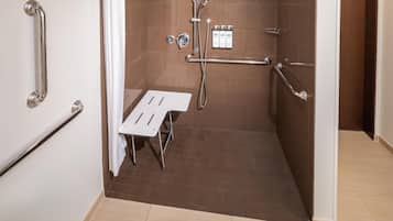 A bathroom with a shower, grab bars, and a white sink.