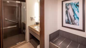 A modern bathroom with a glass shower, a sink with a vanity, and a framed abstract painting on the wall.
