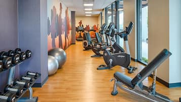A gym with cardio machines, weight benches, and dumbbells.