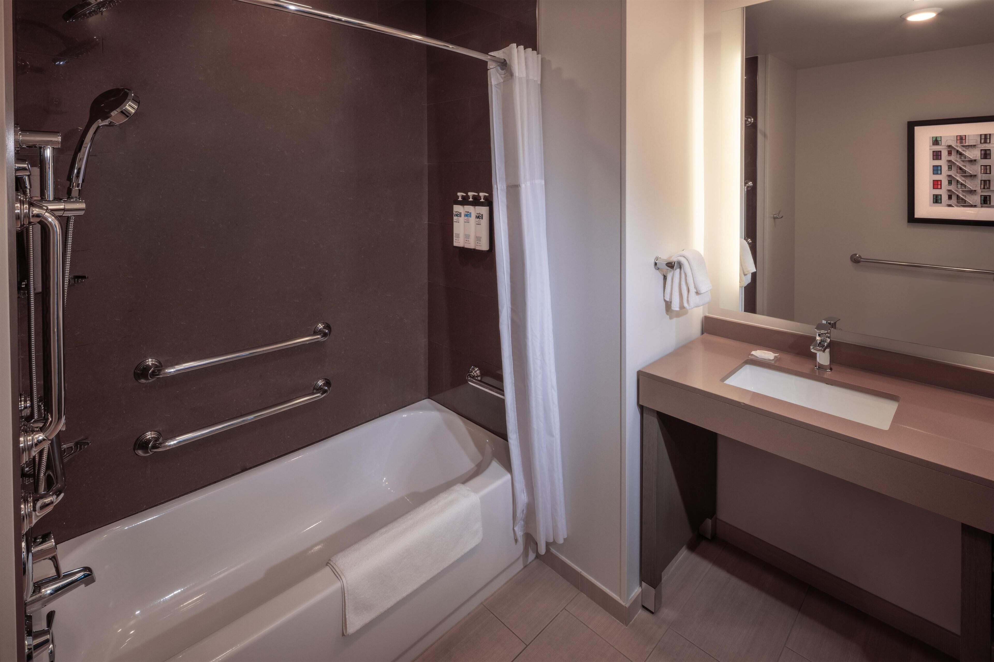 A modern bathroom with a bathtub, shower, and vanity.