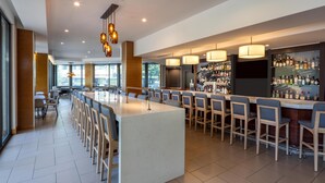 A modern bar area with a long counter, multiple bar stools, and a well-stocked liquor display. - Hyatt House Seattle/Downtown (Seattle)