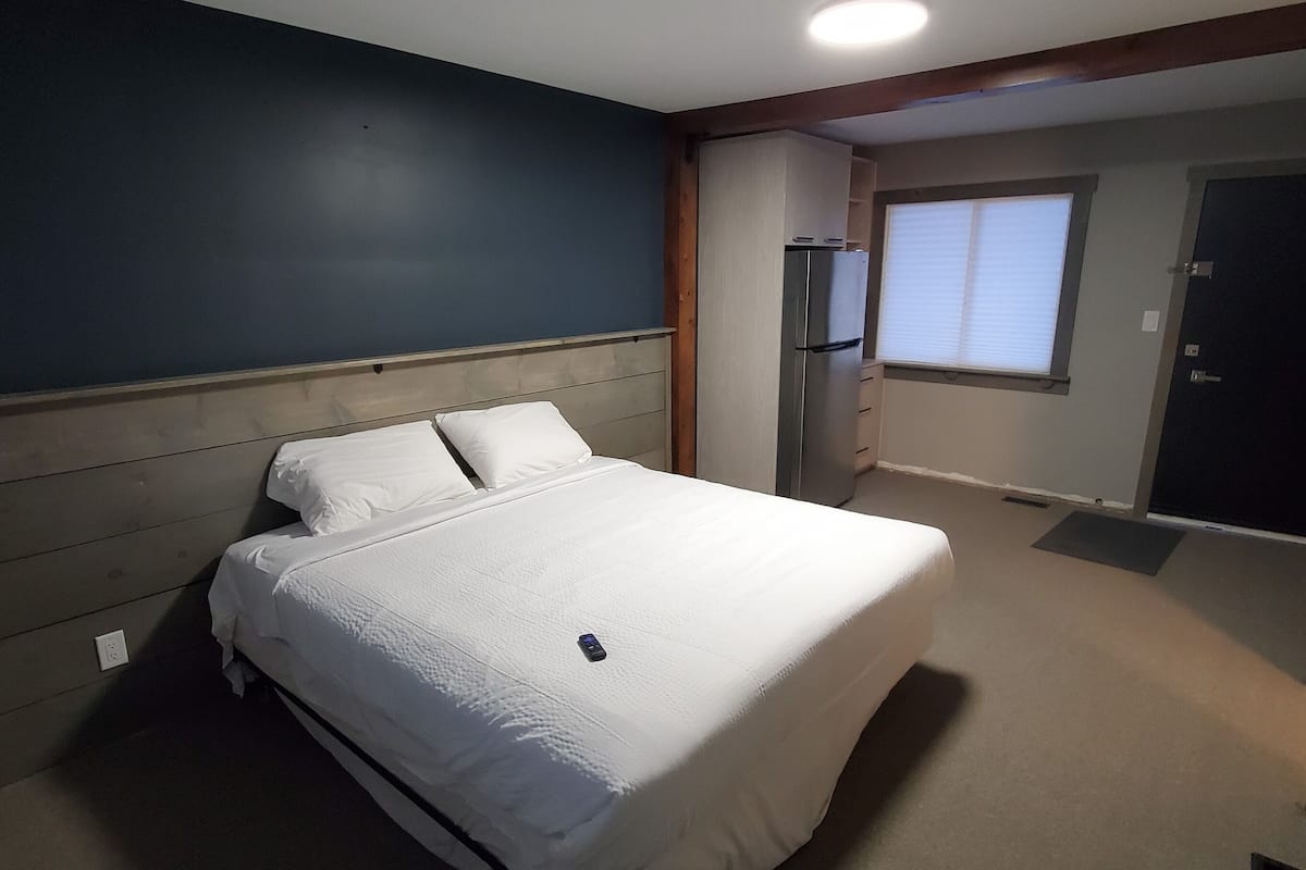 Un dormitorio con cama, armario, ventana y puerta.