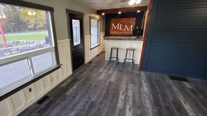 A hotel lobby with a wooden floor, a reception desk, and two bar stools. - Moira Lake Motel (Madoc)
