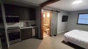 A compact room with a kitchenette, a bed, a toilet, and a TV. - Moira Lake Motel (Madoc)