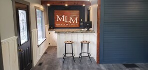 A reception area with a sign reading "MLM Moira Lake Motel," two bar stools, a computer, and a window with a view.
