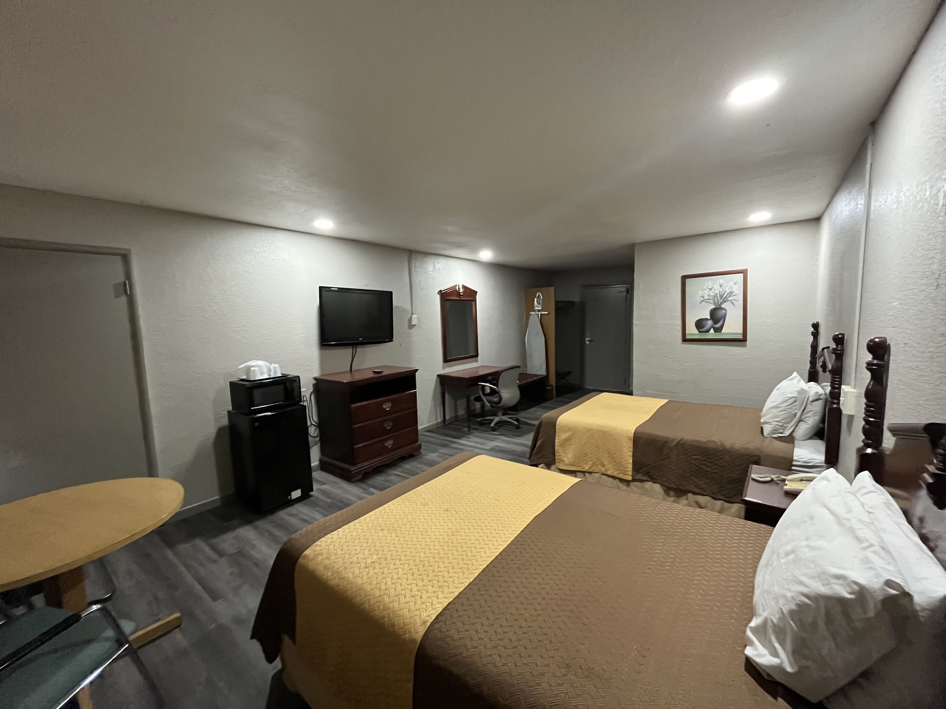 Habitación de hotel con dos camas, un escritorio, una silla, un televisor y una cómoda.