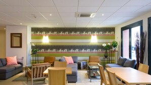 Una sala de estar moderna con sofá, sillas, una mesa de comedor y una pared decorativa con árboles.