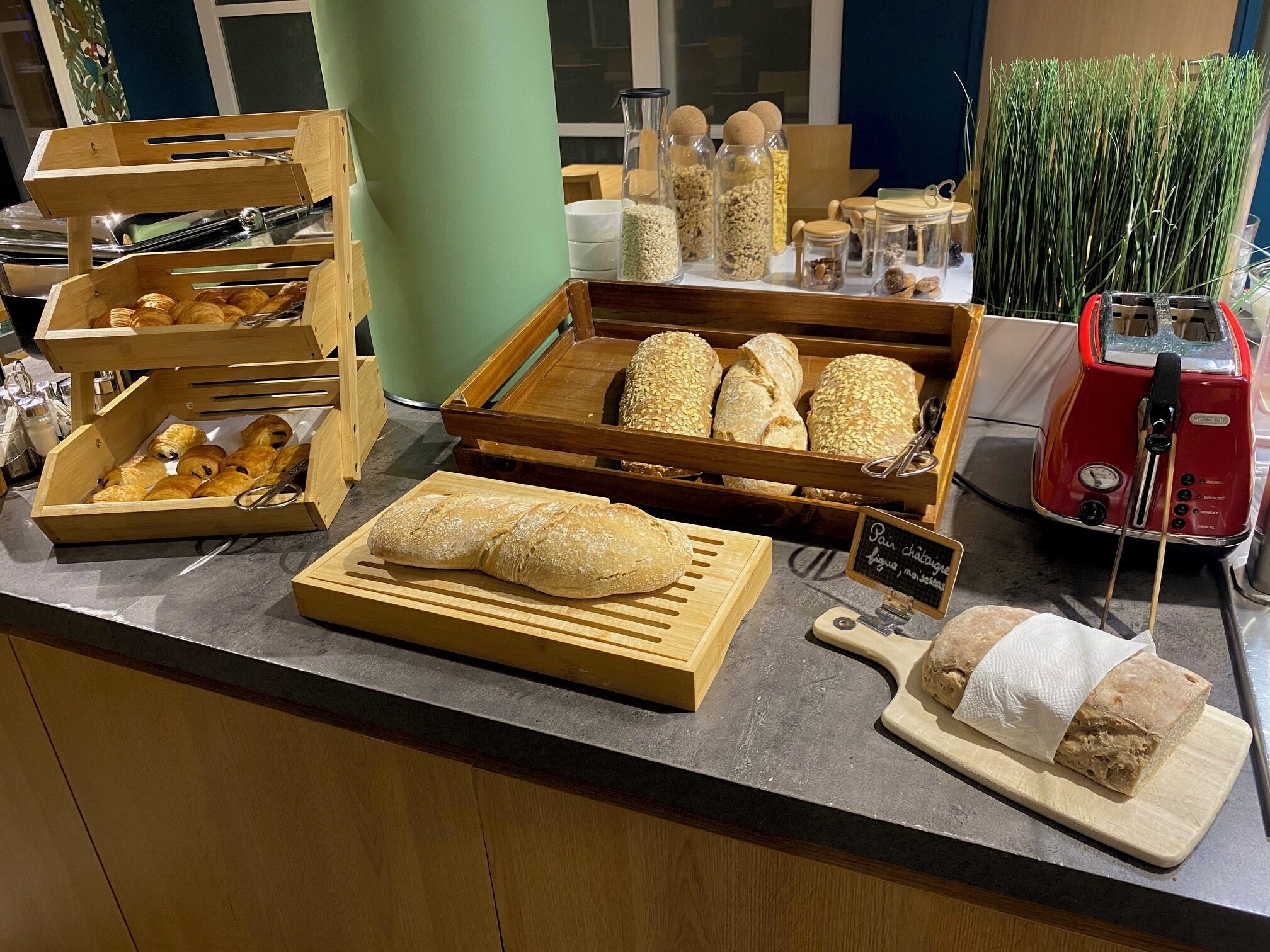Bakkerijvitrine met verschillende broden en gebak, een broodrooster en een bord waarop de beschikbare broedsoorten staan.