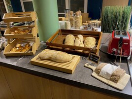 Eine Backvitrine mit verschiedenen Brotsorten und Gebäcken, ein Toaster und ein Schild, das die Brotarten ausweist.