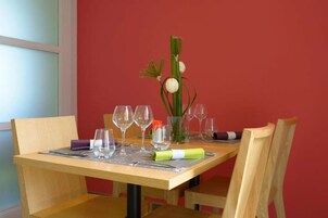 A dining table set with wine glasses, a vase with a flower, and a green napkin.