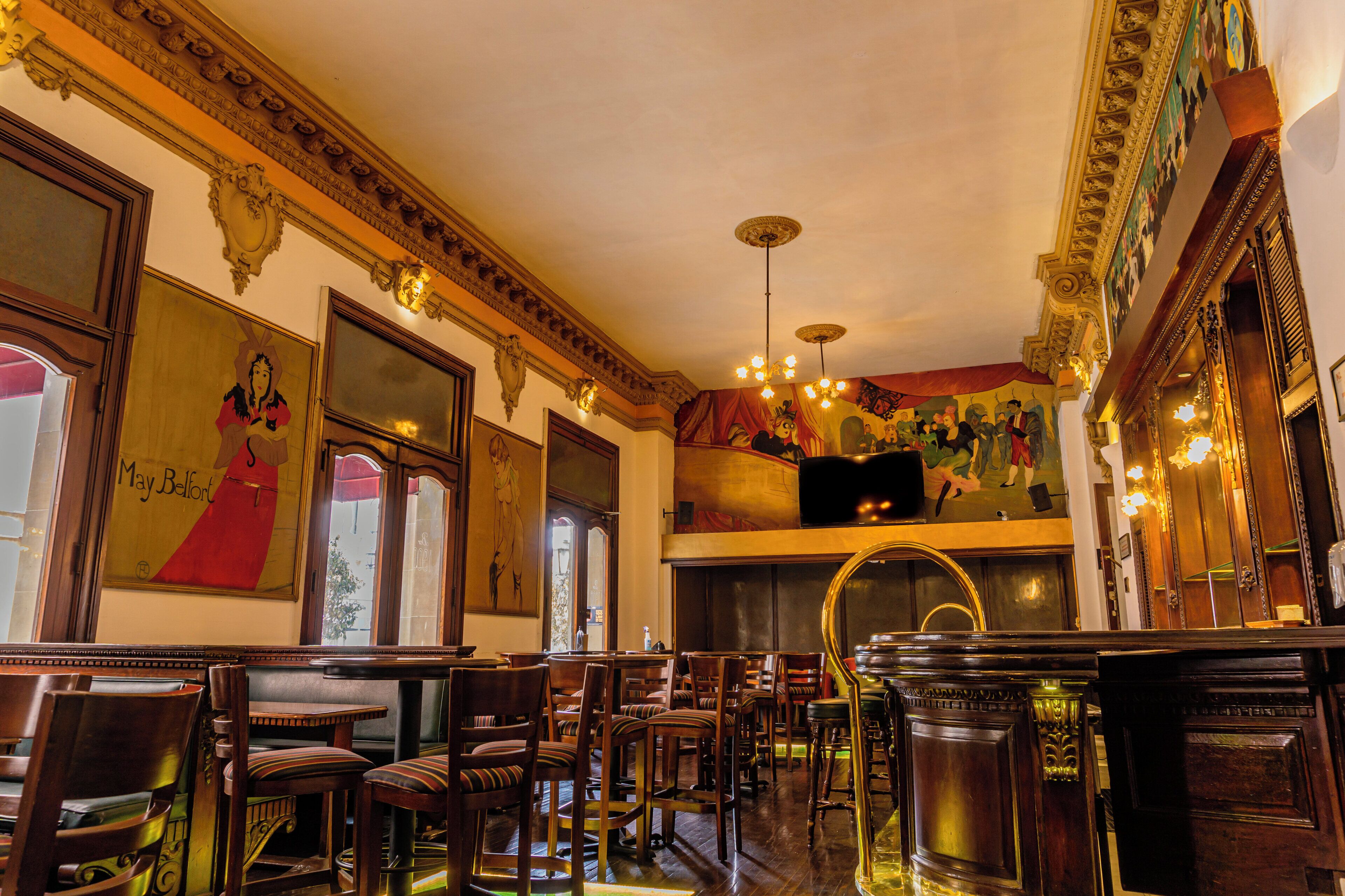 A restaurant interior with wooden furniture, ornate wall decorations, and a chandelier.