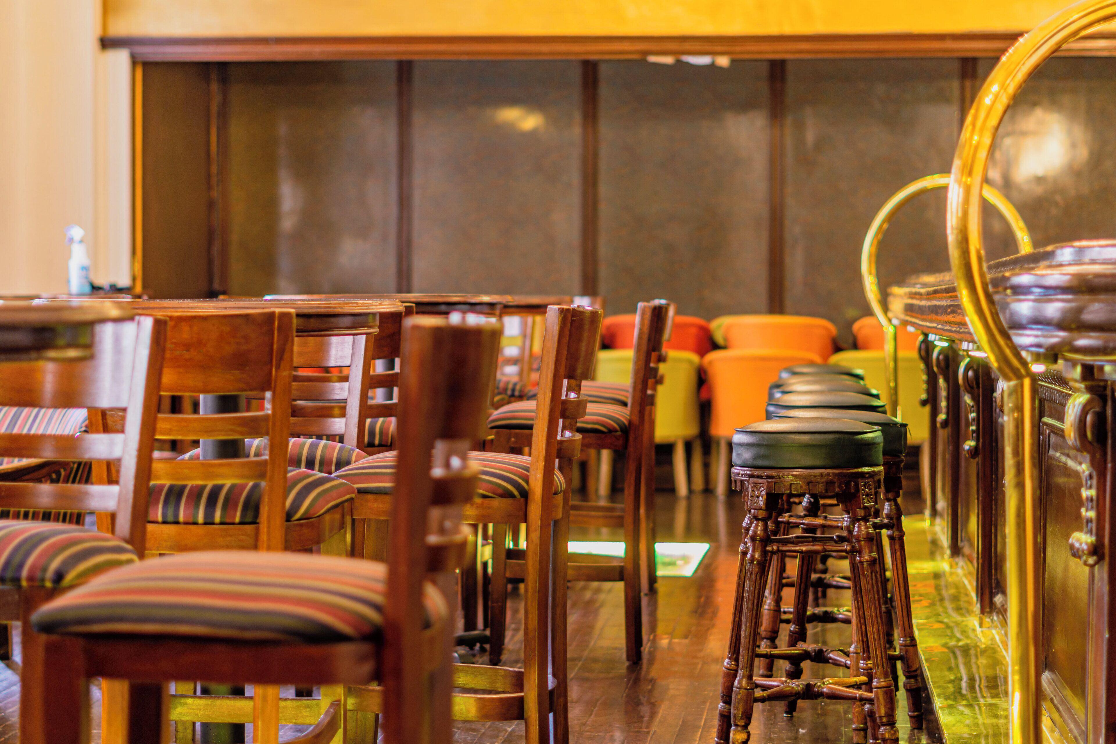 Rows of wooden chairs with striped cushions and a bar area with stools and a bar counter.