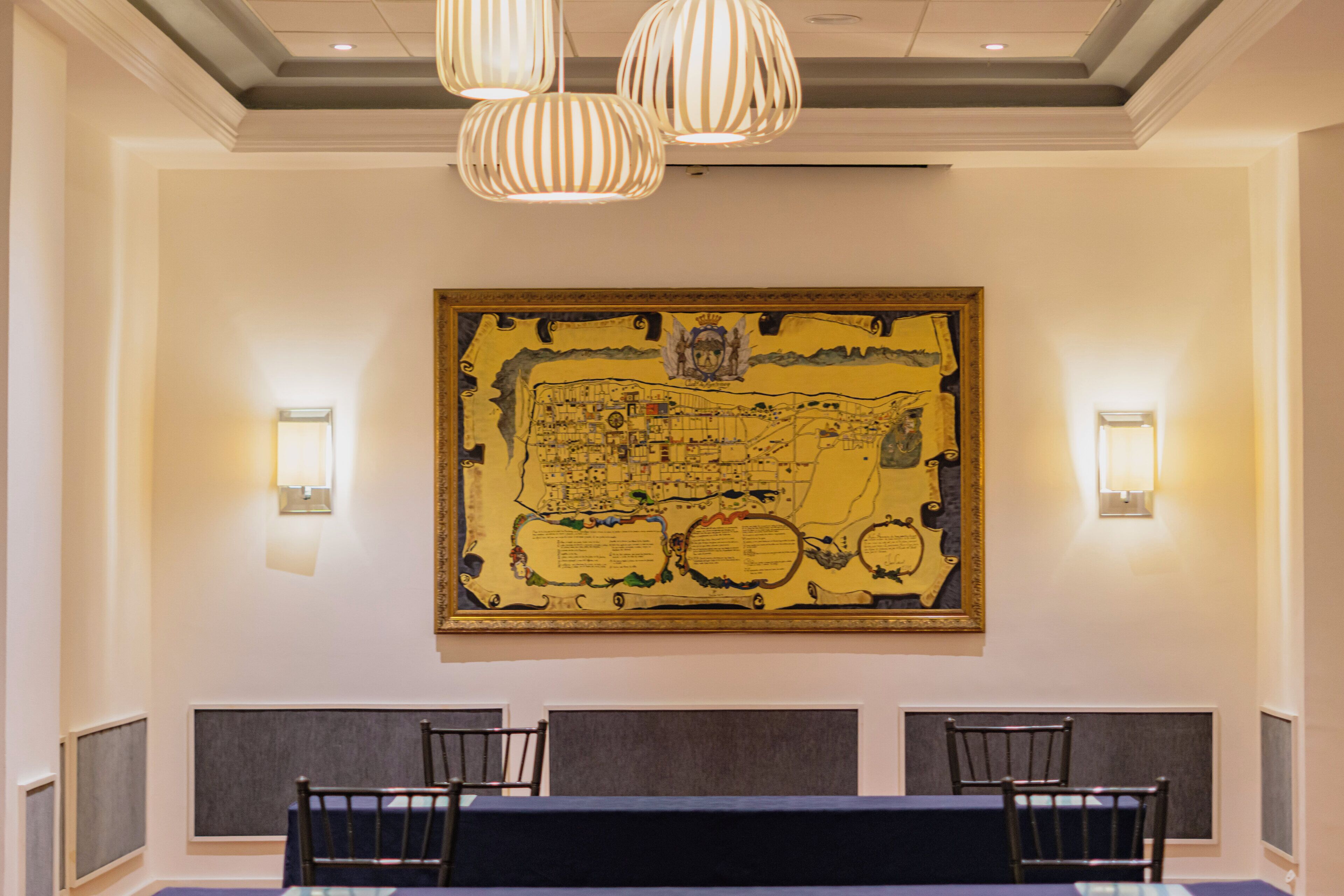 A conference room with a large map on the wall, three chairs, and two pendant lights.