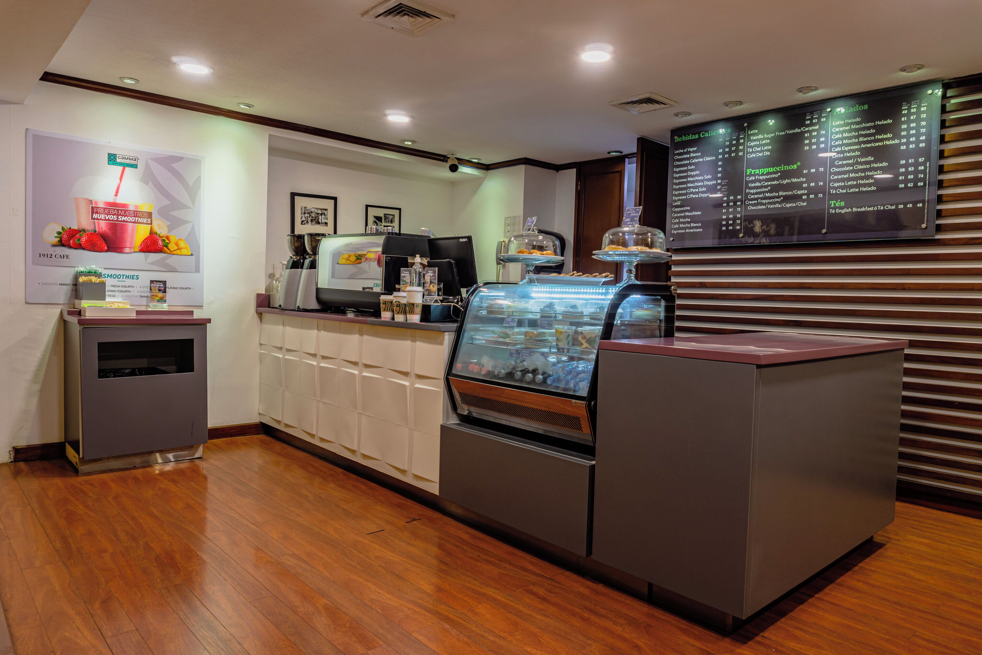A cafe with a menu board, coffee machines, and a display case with pastries.