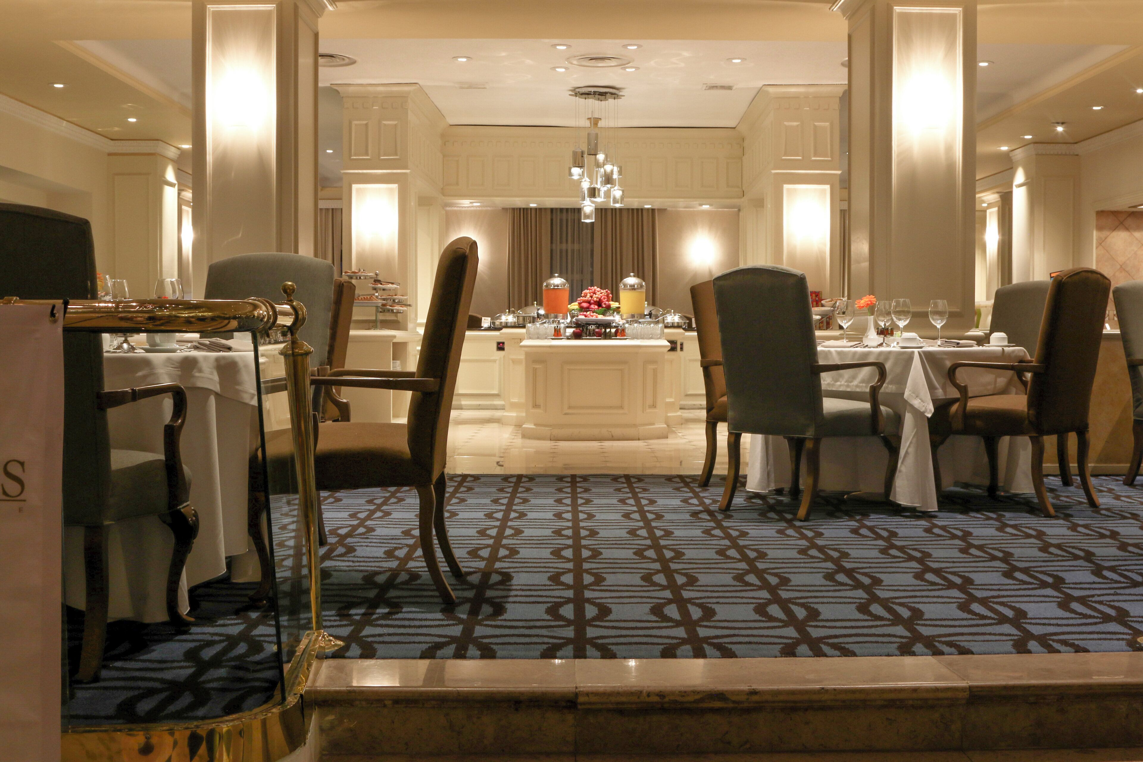 A formal dining area with a central island, multiple tables, and chairs arranged for service.