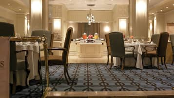 A formal dining area with a central island, multiple tables, and chairs arranged for service.