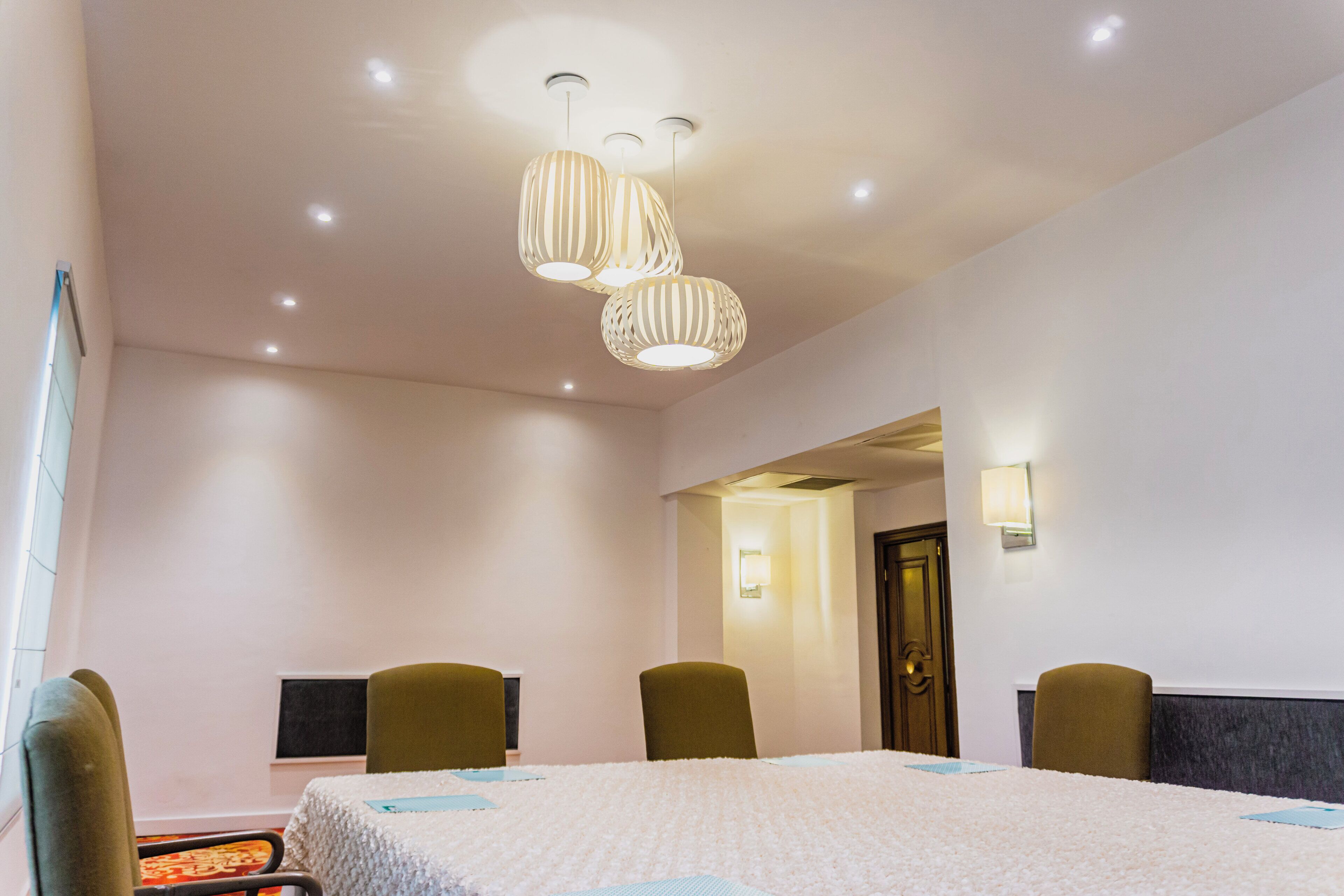 A hotel room with a large bed, two chairs, a desk, and a door leading to another room.