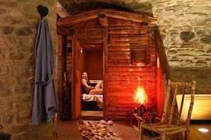 Una cabaña rústica de madera con una pared de piedra, una chimenea y un sillón de madera.