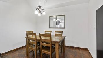 Un coin repas avec une table et des chaises en bois, un luminaire suspendu et un miroir au mur.