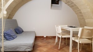 A room with a bed, a table, and chairs. There is a small window and a power outlet on the wall. - Iblea Paradise (Ragusa)